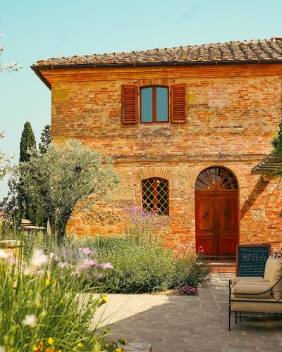 A stone pathway through the manicured gardens leading to the outdoor dining patio of Osteria Le Castelline.